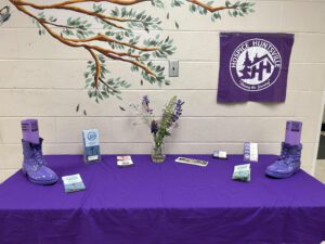 This is a picture of a display table with two purple boots, set up with information about Hop for Hospice at HPS.